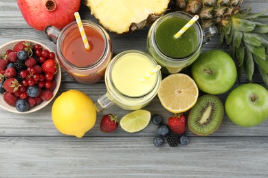 Photo of Superfood. Tasty smoothies in mason jars and ingredients on grey wooden table, flat lay