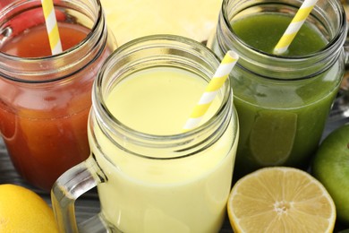 Photo of Superfood. Tasty smoothies in mason jars and ingredients on grey wooden table, closeup