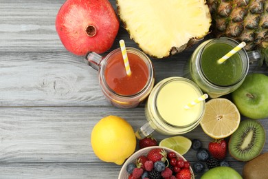 Photo of Superfood. Tasty smoothies in mason jars and ingredients on grey wooden table, flat lay. Space for text