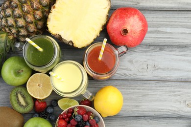 Photo of Superfood. Tasty smoothies in mason jars and ingredients on grey wooden table, flat lay. Space for text