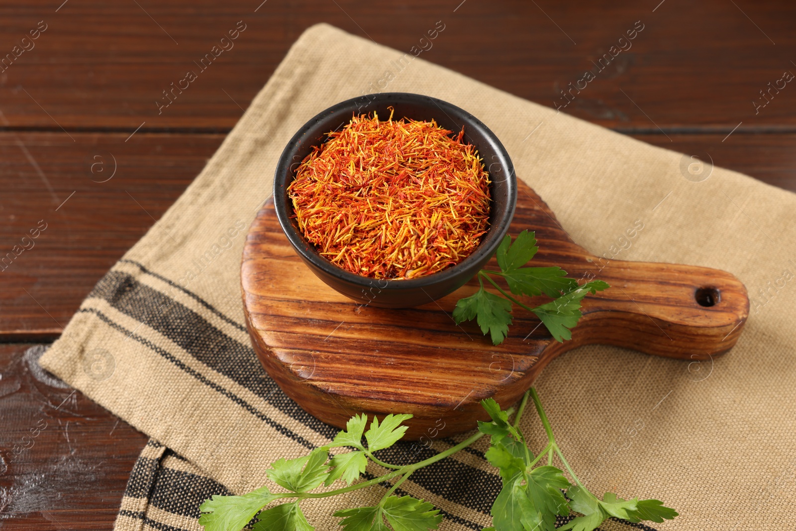 Photo of Saffron in bowl and coriander on wooden table, closeup. Aromatic spices