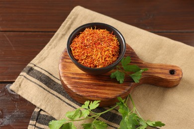 Photo of Saffron in bowl and coriander on wooden table, closeup. Aromatic spices