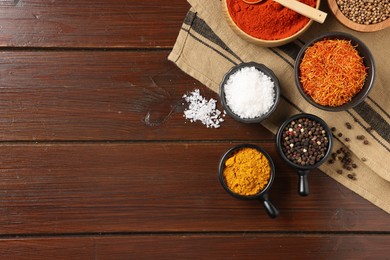 Photo of Different aromatic spices on wooden table, flat lay. Space for text