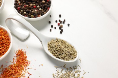 Photo of Different aromatic spices on white marble table, closeup. Space for text
