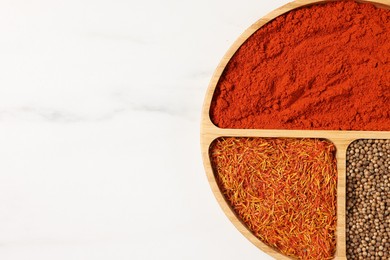 Photo of Different aromatic spices on white marble table, top view. Space for text