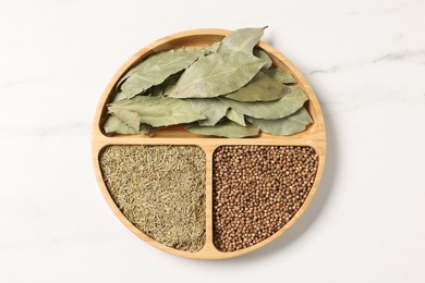 Photo of Different aromatic spices on white marble table, top view