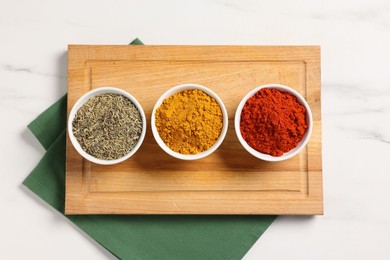 Photo of Different aromatic spices on white marble table, top view