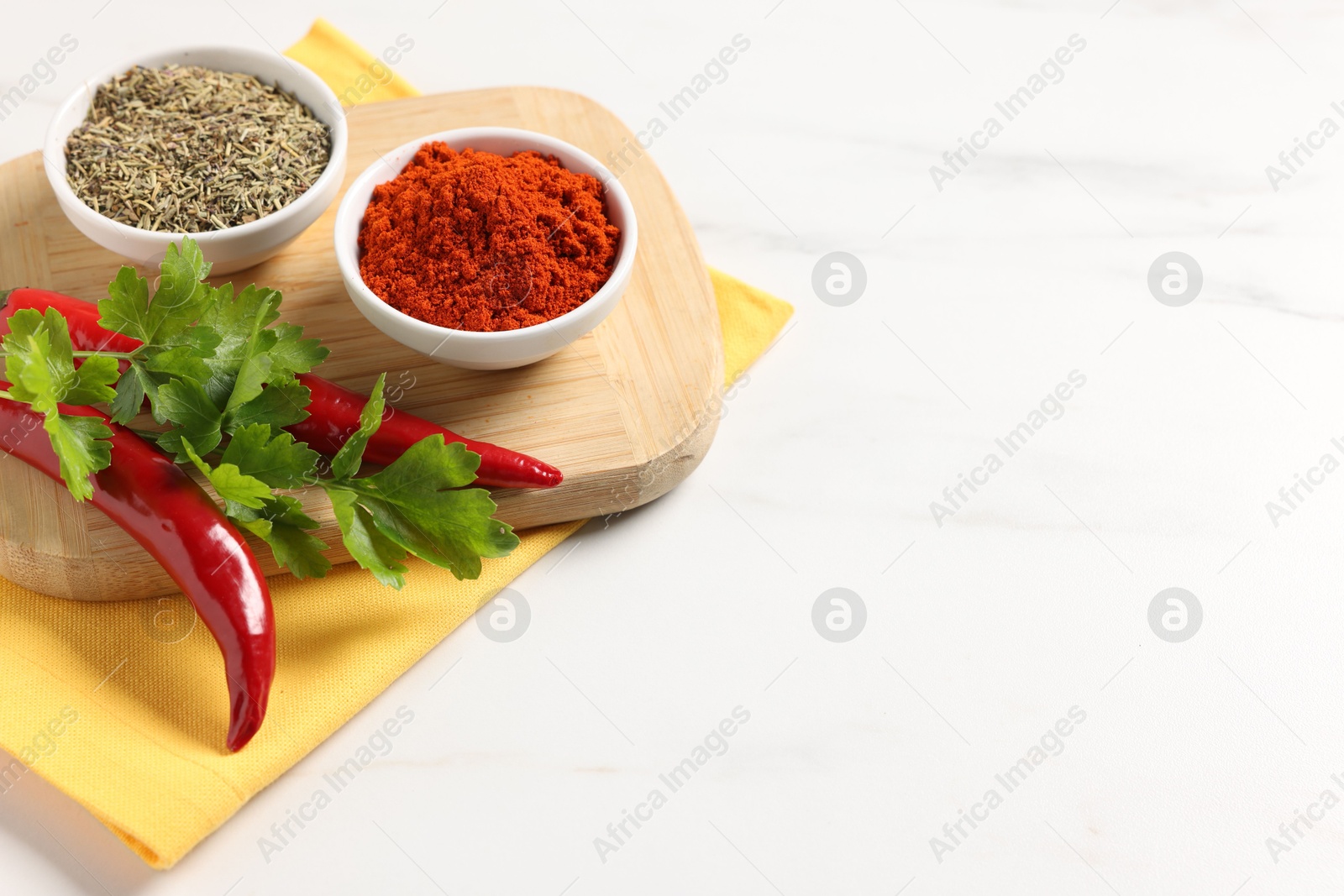 Photo of Different aromatic spices on white marble table, closeup. Space for text