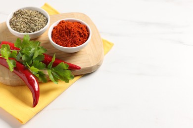 Photo of Different aromatic spices on white marble table, closeup. Space for text