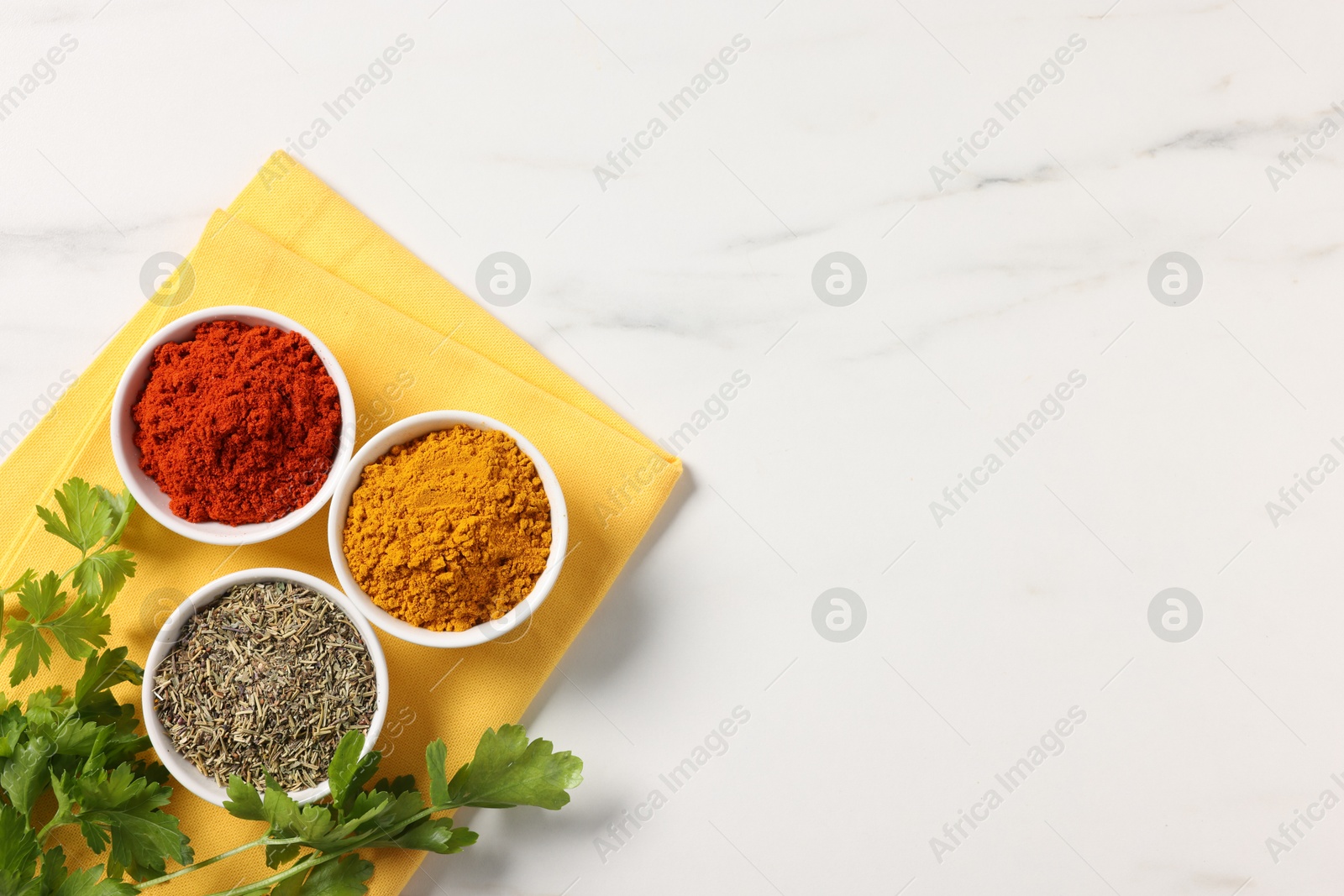 Photo of Different aromatic spices on white marble table, top view. Space for text