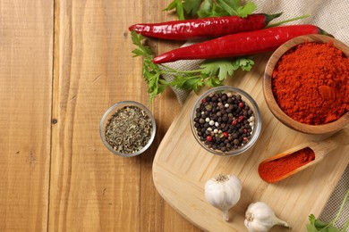 Photo of Different aromatic spices on wooden table, flat lay. Space for text
