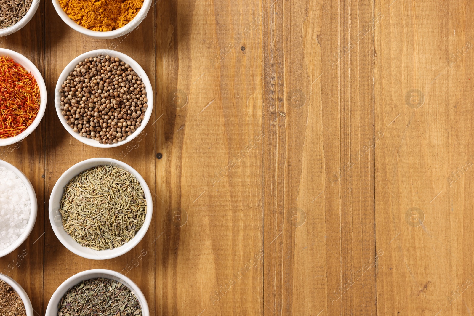 Photo of Different aromatic spices on wooden table, flat lay. Space for text