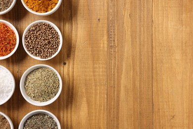 Photo of Different aromatic spices on wooden table, flat lay. Space for text
