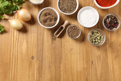 Photo of Different aromatic spices on wooden table, flat lay. Space for text