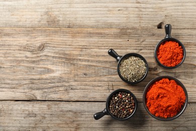 Photo of Different aromatic spices on wooden table, flat lay. Space for text