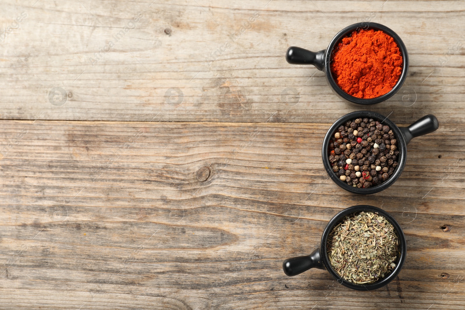 Photo of Different aromatic spices on wooden table, flat lay. Space for text