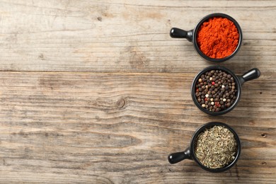 Photo of Different aromatic spices on wooden table, flat lay. Space for text