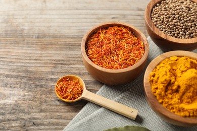 Photo of Different aromatic spices on wooden table, closeup. Space for text