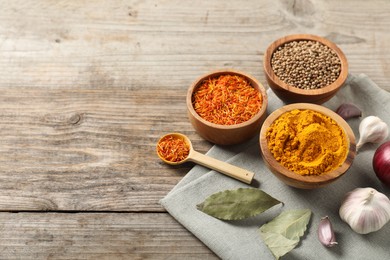 Photo of Different aromatic spices on wooden table. Space for text