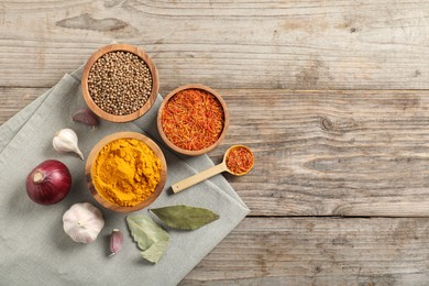 Photo of Different aromatic spices on wooden table, flat lay. Space for text