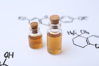 Photo of Bottles of cosmetic products on paper with chemical formulas, closeup