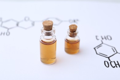 Photo of Bottles of cosmetic products on paper with chemical formulas, closeup