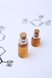 Photo of Bottles of cosmetic products on paper with chemical formulas, closeup