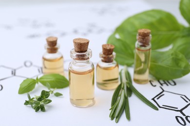 Photo of Different herbs and bottles of cosmetic products on paper with chemical formulas, closeup