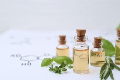 Photo of Different herbs and bottles of cosmetic products on paper with chemical formulas, closeup. Space for text