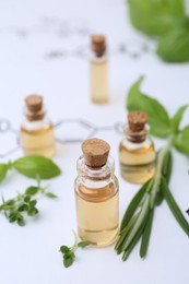 Photo of Different herbs and bottles of cosmetic products on paper with chemical formulas, closeup