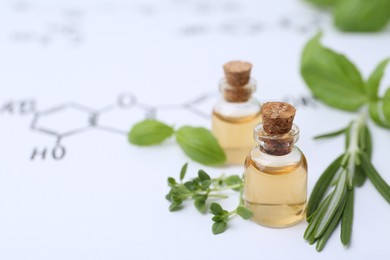 Photo of Different herbs and bottles of cosmetic products on paper with chemical formulas, closeup. Space for text