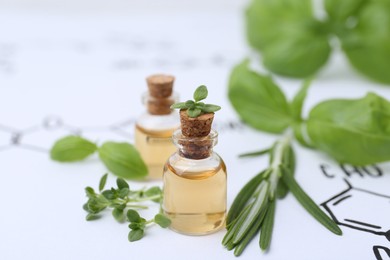 Photo of Different herbs and bottles of cosmetic products on paper with chemical formulas, closeup