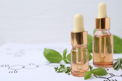 Photo of Different herbs and bottles of cosmetic products on paper with chemical formulas, closeup. Space for text