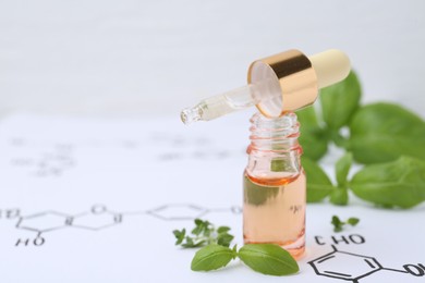 Photo of Different herbs and bottle of cosmetic product on paper with chemical formulas, closeup. Space for text