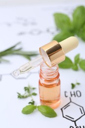 Photo of Different herbs and bottle of cosmetic product on paper with chemical formulas, closeup