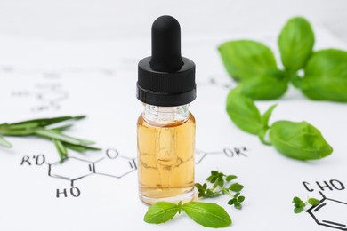 Photo of Different herbs and bottle of cosmetic product on paper with chemical formulas, closeup