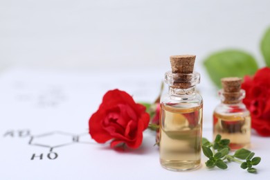 Photo of Bottles of cosmetic products, herbs and red roses on paper with chemical formulas, closeup. Space for text
