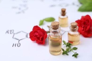 Photo of Bottles of cosmetic products, herbs and red roses on paper with chemical formulas, closeup. Space for text