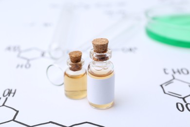 Photo of Bottles of cosmetic products, test tubes and Petri dish of sample on paper with chemical formulas, closeup