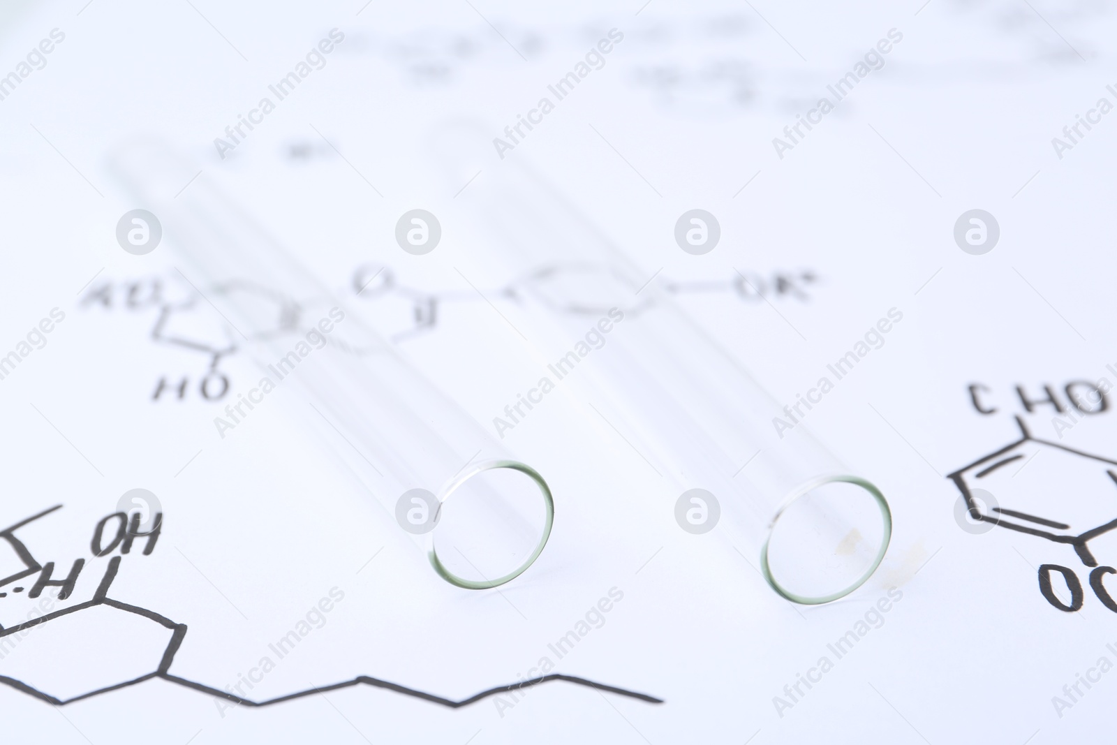 Photo of Test tubes on paper with chemical formulas, closeup
