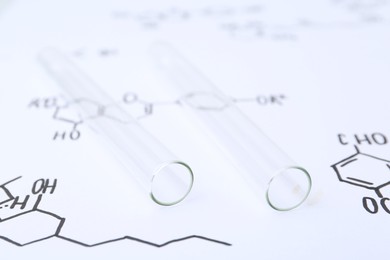 Photo of Test tubes on paper with chemical formulas, closeup