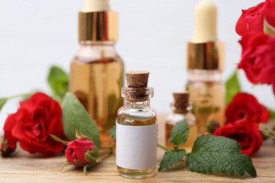 Photo of Bottles of essential oils, red roses and herbs on wooden table, closeup