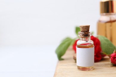 Photo of Bottles of essential oils, red roses and herbs on table, closeup. Space for text