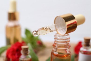Photo of Bottle of essential oil and dropper on blurred background, closeup