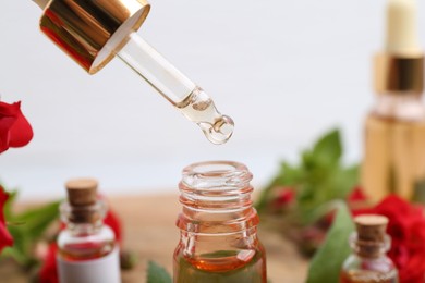Photo of Dripping essential oil into bottle on blurred background, closeup