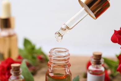 Photo of Dripping essential oil into bottle on blurred background, closeup