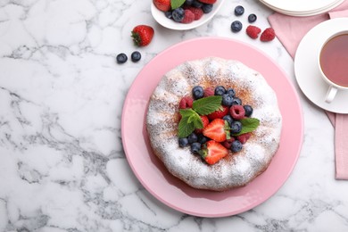 Photo of Tasty Bundt cake with powdered sugar and berries on white marble table, flat lay. Space for text