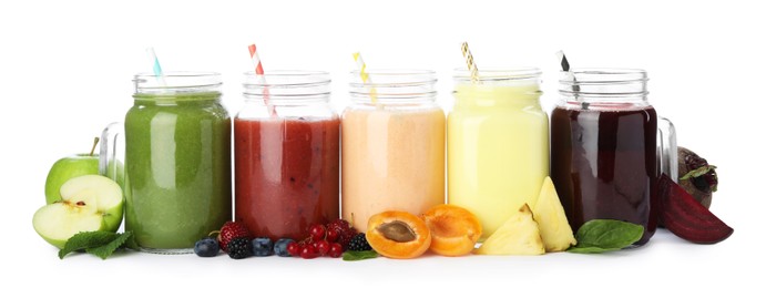 Photo of Superfood. Different tasty smoothies in mason jars and ingredients isolated on white