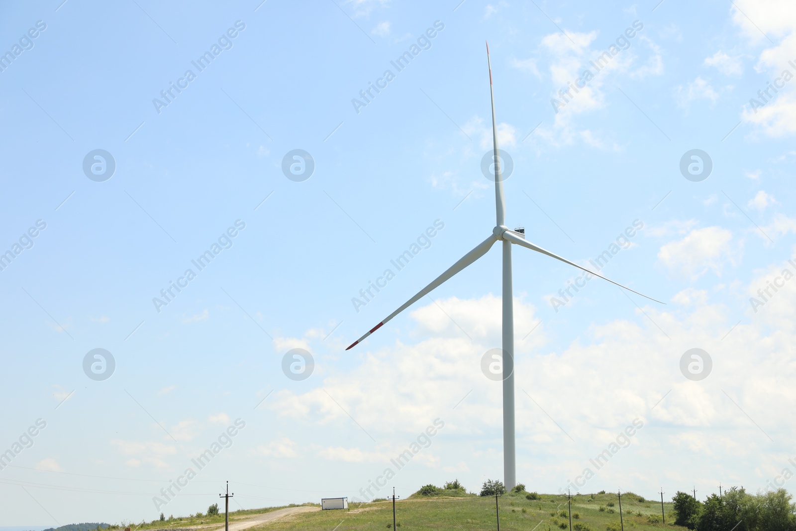 Modern wind turbine in field on sunny day. Space for text Photo of Modern wind turbine in field on sunny day. Space for text
