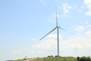 Photo of Modern wind turbine in field on sunny day. Space for text